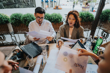 A diverse group of business people sitting at a coffee bar, discussing and analyzing ideas and projects together. They are engaged in a dynamic brainstorming session with documents and laptops.