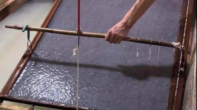 A workshop worker demonstrates traditional Chinese papermaking techniques