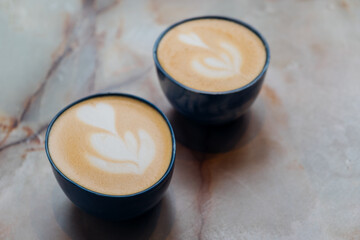 Two cups of fresh delicious cappuccino coffee with beautiful latte art on marble background. ...