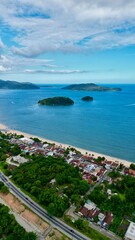 Obraz premium Linda vista aerea com drone sobre o mar com montanhas e cidade ao fundo com cores vibrantes.