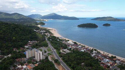 Linda vista aerea com drone sobre o mar com montanhas e cidade ao fundo com cores vibrantes.