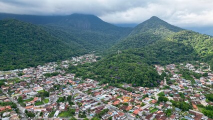 Linda vista aerea com drone sobre o mar com montanhas e cidade ao fundo com cores vibrantes.