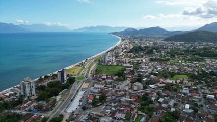 Fototapeta premium Linda vista aerea com drone sobre o mar com montanhas e cidade ao fundo com cores vibrantes.