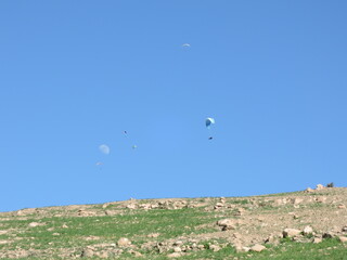 Aerial view of powered paraglider flying over mountainous landscape and forests, concept of adventure sports and aerial freedom