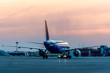 Airplane ready to fly at the airport with the backdrop of a blue and crimson sunset scenic sky with...