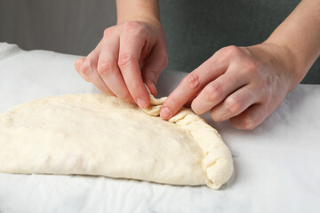 Woman making calzone pizza at table, closeup