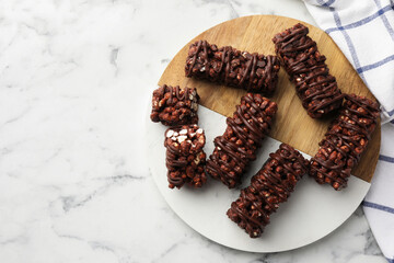 Delicious chocolate puffed rice bars on white marble table, top view. Space for text