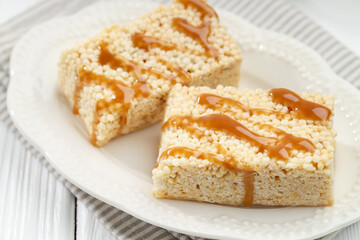 Delicious caramel puffed rice bars on white wooden table, closeup