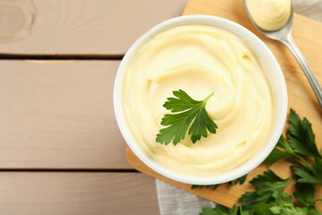 Delicious mayonnaise sauce with parsley in bowl on wooden table, top view. Space for text