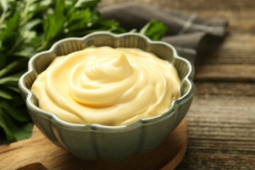 Delicious mayonnaise sauce in bowl on wooden table, closeup