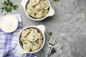 Delicious dumplings served on grey table, flat lay. Space for text