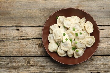 Tasty dumplings with green onion on wooden table, top view. Space for text