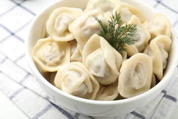 Tasty dumplings and dill in bowl on white table, closeup
