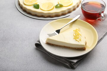 Piece of tasty lemon cheesecake on grey textured table, closeup. Space for text