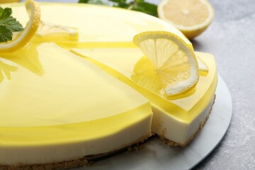 Tasty lemon cheesecake with mint on grey textured table, closeup