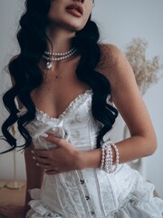 Sensual sexy woman in bridal erotic satin bodysuit with bow on bust and lace posing in bedroom.