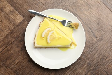 Piece of delicious cheesecake with lemon curd on wooden table, top view