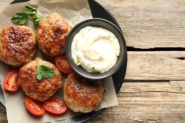 Delicious patties, parsley, tomatoes and sauce on wooden table, top view. Space for text