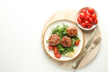 Delicious patties with greens, tomatoes and cutlery on white table, top view. Space for text