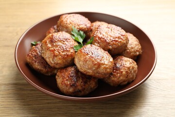 Delicious patties with parsley on wooden table, closeup