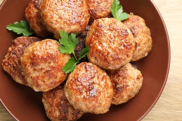 Delicious patties with parsley on wooden table, top view