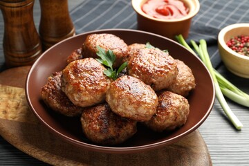 Delicious patties and spices on black textured table, closeup