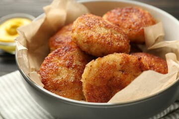 Tasty patties in bowl on table, closeup