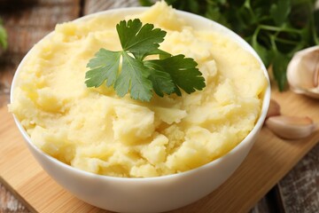 Delicious mashed potato with parsley served on wooden table, closeup