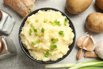 Delicious mashed potato with green onions served on grey table, flat lay