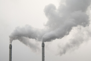 factory chimneys with smoke coming out, gray sky in the background