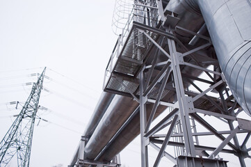 pipeline and power transmission tower against gray sky