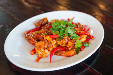 Thai food of spicy shrimp with curry, herb and red pepper on white plate
