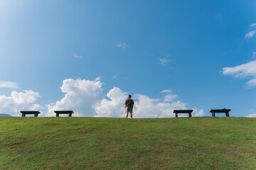 Man standing on green hill and blue sky in sunny day