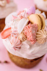 Traditional Ukrainian easter bread or sweet paska bread with topping decorated with cream and colorful meringue, macarons and eggs