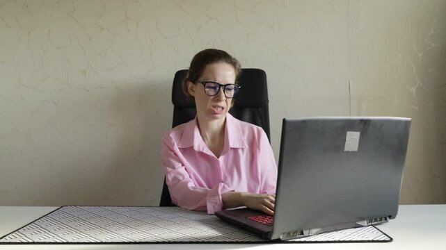 woman in office looking at laptop with disgust, professional employee thinking about online business, emotion of aversion during remote work