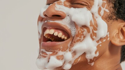 Naklejka premium A young man applying shaving cream to his face, captured in a close-up photograph with white liquid dripping off him.
