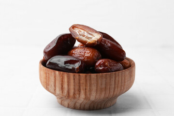 Tasty dried dates in bowl on white table, closeup
