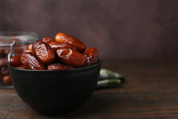 Tasty dried dates in bowl on wooden table, closeup. Space for text