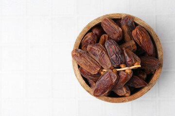Tasty dried dates on white tiled table, top view. Space for text