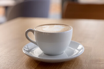 Cup of aromatic coffee on wooden table in cafe, closeup