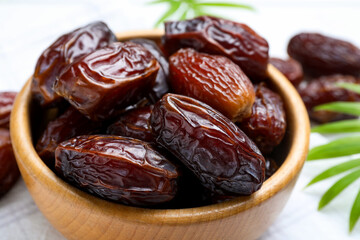 Tasty dried dates and leaves on white table, closeup