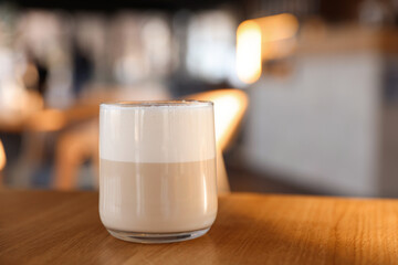 Glass of aromatic coffee on wooden table in cafe, closeup. Space for text