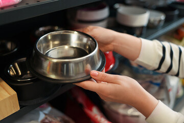 Woman choosing feeding bowl in pet shop, closeup