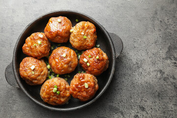 Tasty meatballs with green onion in baking dish on grey table, top view. Space for text