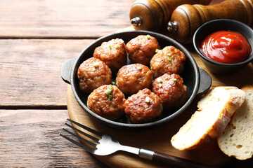 Tasty meatballs with green onion in baking dish served on wooden table