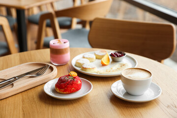 Delicious cottage cheese pancakes, dessert and coffee served on wooden table in cafe