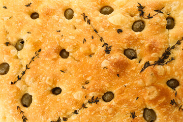 Delicious focaccia bread with olives and thyme as background, top view