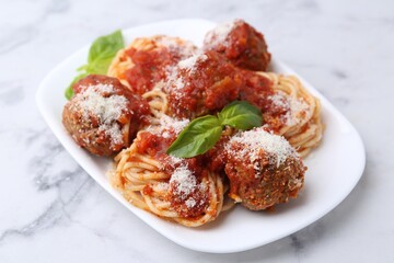 Delicious pasta with meatballs, basil and cheese on white marble table, closeup