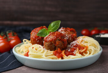 Delicious pasta with meatballs, basil and cheese on brown textured table, closeup