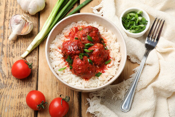 Tasty meatballs with sauce, rice and products on wooden table, flat lay